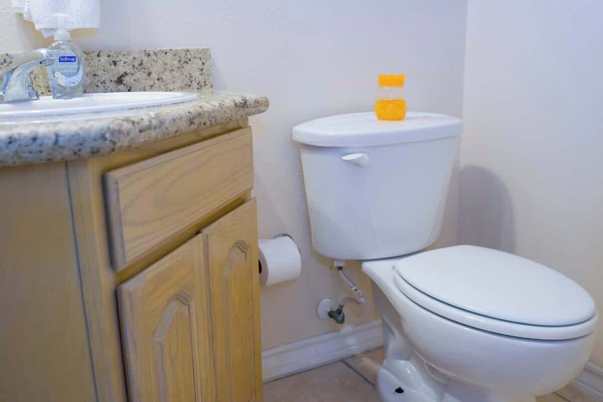 A bathroom with a white toilet, a sink with a soap dispenser, and a toilet paper holder.