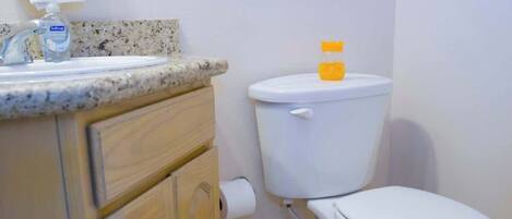 A bathroom with a white toilet, a sink with a soap dispenser, and a toilet paper holder.