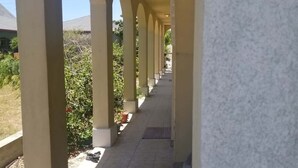 A covered corridor with arches, tiled flooring, and potted plants along the sides. - Oversized 2 Bedroom - Modern - Pool Near Beach (South Padre Island)