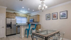 A kitchen with a refrigerator, microwave, and island with bar stools. - Oversized 2 Bedroom - Modern - Pool Near Beach (South Padre Island)