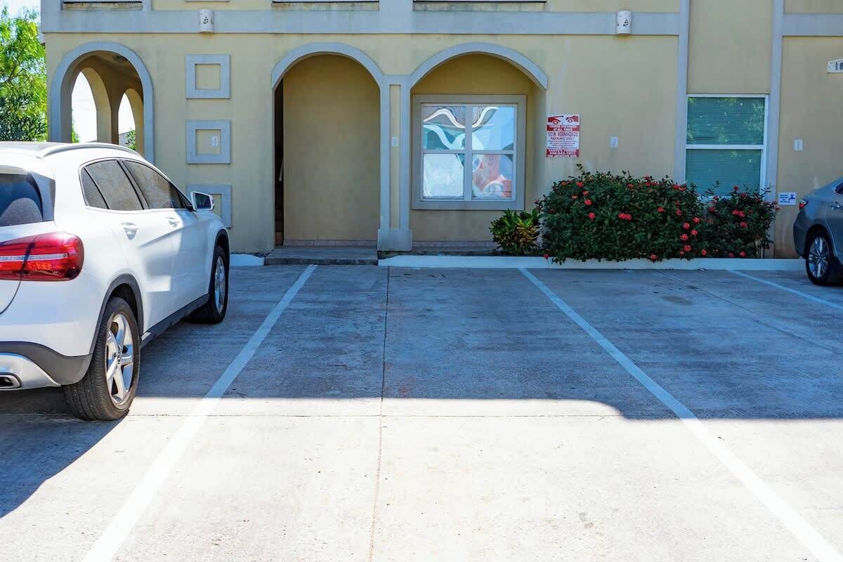 Un estacionamiento con un edificio que tiene arcos y una ventana con un letrero.