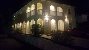 A two-story building with a symmetrical facade, multiple arched windows, and a central balcony. - Oversized 2 Bedroom - Modern - Pool Near Beach (South Padre Island)