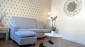 A modern living room with a grey sofa, a round coffee table, and a patterned wallpaper. - Modern 3 bedrooms house with 6 guests (Sheffield)