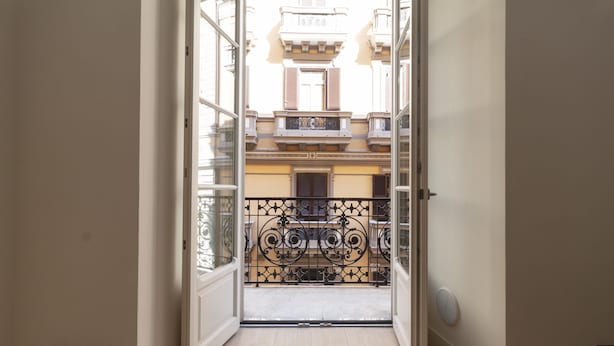 A corridor leading to a balcony with a wrought iron railing, a door with a handle, and a light switch on the wall. - Palazzo Nan 3 Piano Scala C (Naples)