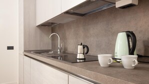 A modern kitchen with a stainless steel sink, a kettle, and two white cups on the countertop. - Palazzo Nan 3 Piano Scala C (Naples)