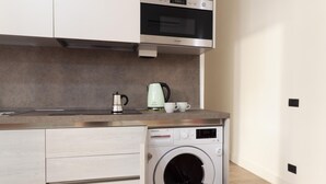 A compact kitchen with a built-in washing machine, a coffee maker, and a microwave. - Palazzo Nan 3 Piano Scala C (Naples)