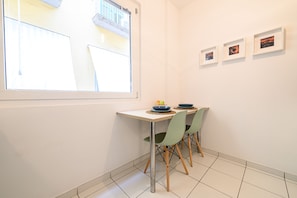 Un coin repas avec une table et des chaises, une fenêtre et trois tableaux encadrés accrochés au mur.