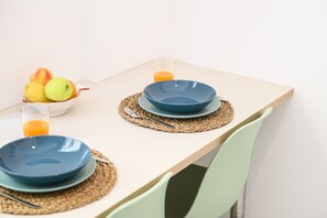 A dining table set with a bowl of fresh fruits and a glass of juice, accompanied by a chair.