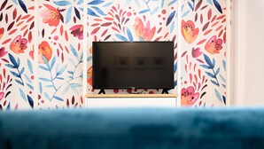 En platt-TV monterad på ett trästativ, placerad mot en vägg med en blommig tapet.