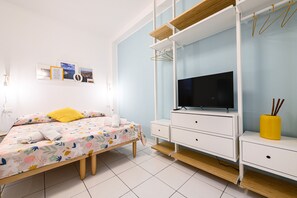 A bedroom with a bed, a TV, a dresser, and a wall-mounted shelf. - Via S Liborio - 1 Piano (Naples)
