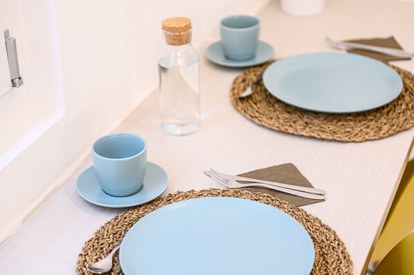 A neatly set dining table with blue plates, a clear glass bottle, and a woven placemat. - Via S Liborio - 1 Piano (Naples)