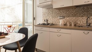 A modern kitchen with white cabinets, a tiled backsplash, a gas stove, a coffee maker, and a sink. - Via Nilo 20 Appartamento Grande (Naples)