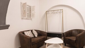 A room with a brown leather sofa, a white side table, and a black dresser. - Via Nilo 20 Appartamento Grande (Naples)