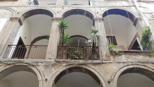 A historic building with multiple arches and balconies, some with plants. - Via Nilo 20 Appartamento Grande (Naples)
