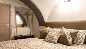 A bedroom with a patterned bedspread, a headboard, and a mirror above a wardrobe. - Via Nilo 20 Appartamento Grande (Naples)