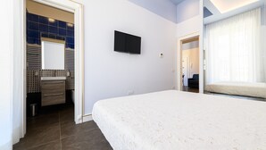 A modern hotel room with a large bed, a TV mounted on the wall, and a bathroom with a mirror and sink. - Corso Umberto 58 in Napoli (Naples)