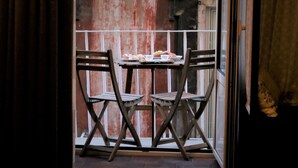 A balcony with a table set for two, featuring a plate of food, two chairs, and a view of a red brick wall. - Napolicentrico in Napoli (Naples)