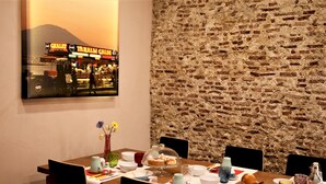 A dining area with a brick wall, a table set with plates, cups, and a dessert display. - Napolicentrico in Napoli (Naples)