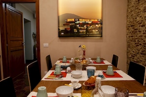 A dining table set with various dishes and drinks, a framed picture on the wall, and a brick wall to the right.
