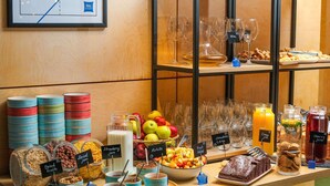Un bufé con diversas opciones de comida y bebidas, incluyendo frutas, nueces y postres.