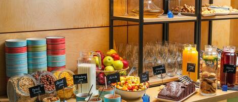 A buffet with various food items and drinks, including fruits, nuts, and desserts.