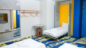 A hotel room with a bed, a small stool, a mirror, a TV, and a wardrobe.