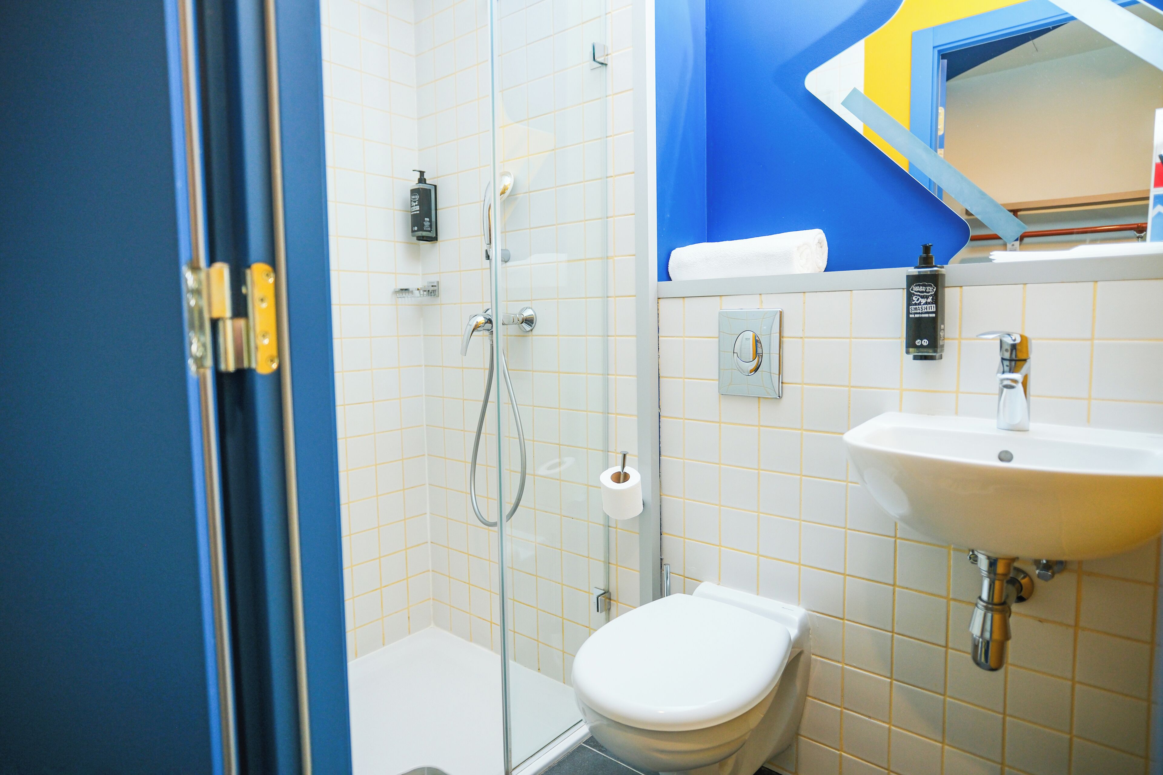 A bathroom with a glass shower enclosure, a white toilet, and a sink with a mirror above it.