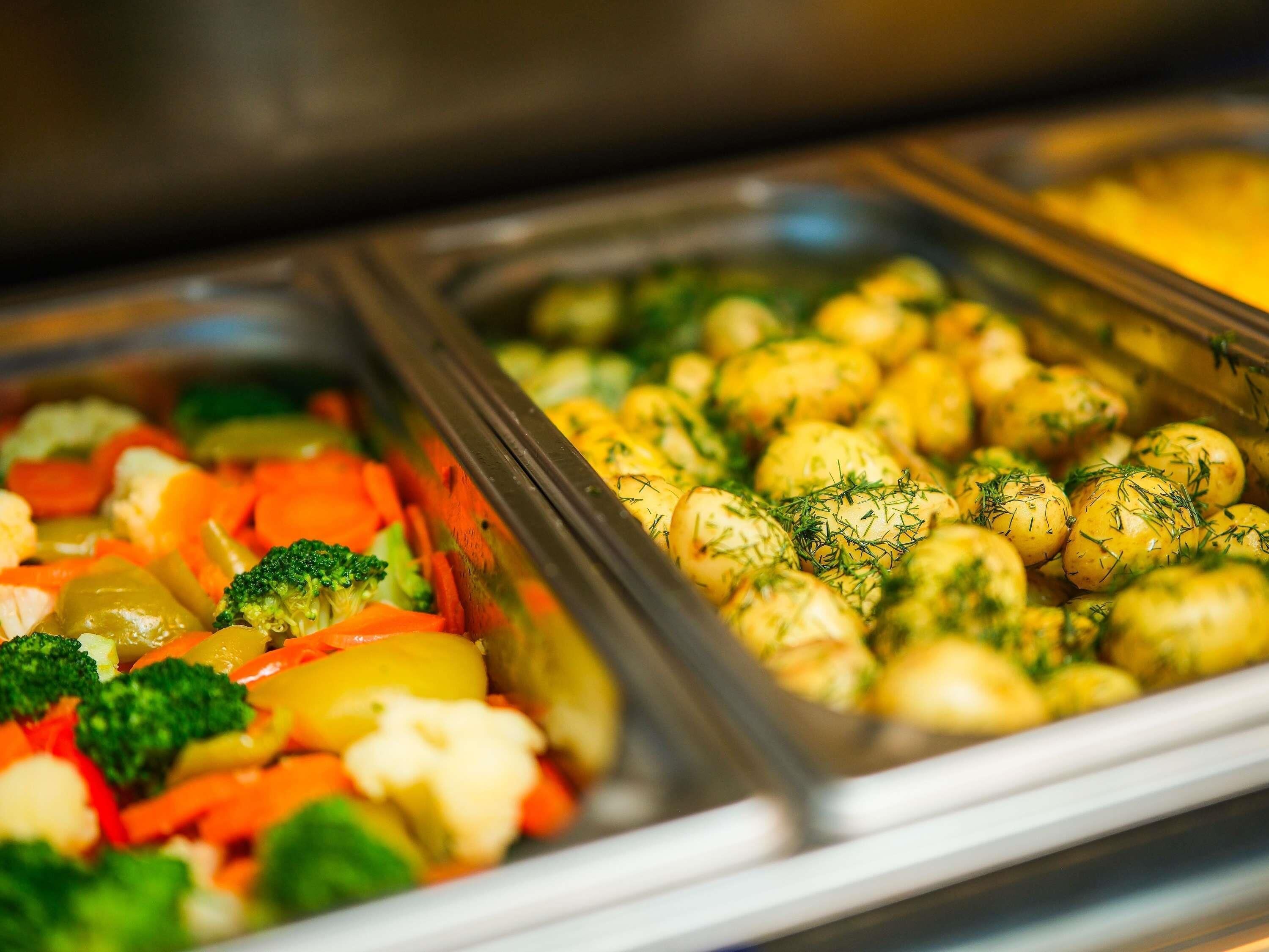 Ein Buffet mit verschiedenen Speisen, darunter Gemüse und Kartoffeln.