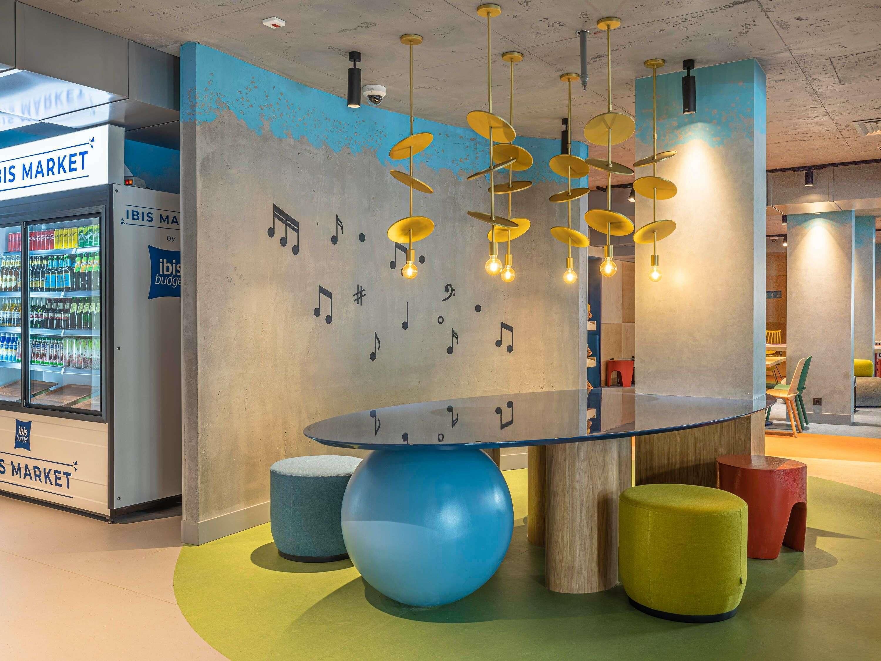A modern interior with a glass table, colorful stools, and a wall with musical notes.