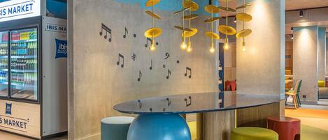 Un intérieur moderne avec une table en verre, des tabourets colorés et un mur décoré de notes de musique.