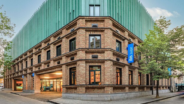 A building with a brick facade and a modern green structure behind it. - Ibis Budget Tbilisi Center (Tbilisi)