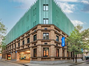 A building with a brick facade and a modern green structure behind it. - Ibis Budget Tbilisi Center (Tbilisi)