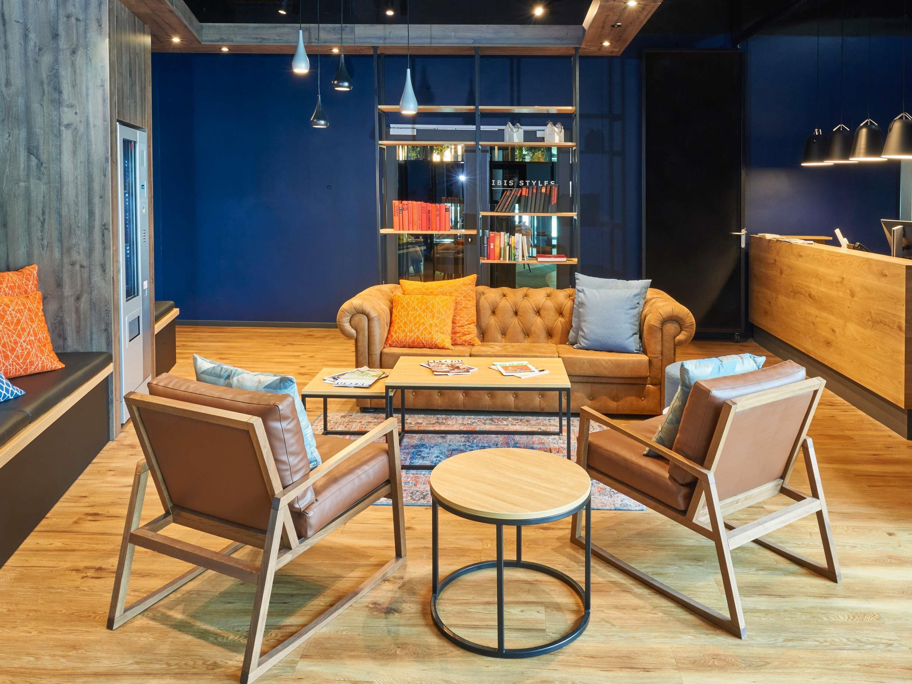 Un área de estar moderna con sofás de cuero, una mesa de centro y una estantería llena de libros.