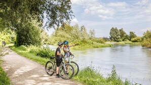 A paved path beside a river with cyclists and a person pointing towards the water. - Ibis Budget Singen (Singen)