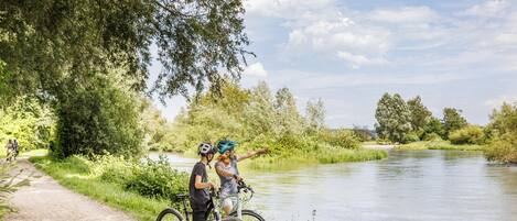 A paved path beside a river with cyclists and a person pointing towards the water.
