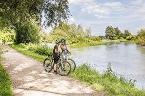 A paved path beside a river with cyclists and a person pointing towards the water. - Ibis Budget Singen (Singen)