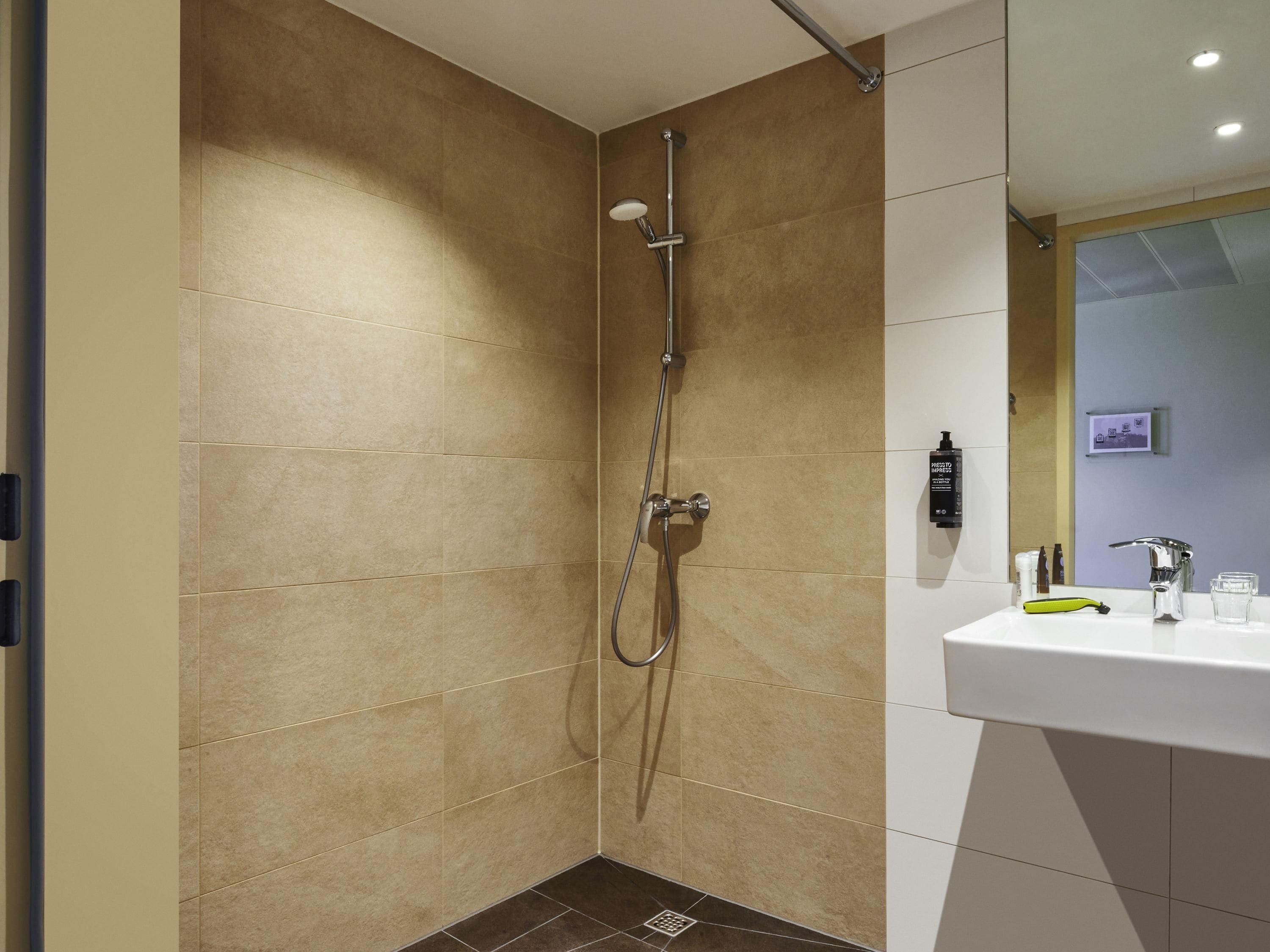 Un baño moderno con ducha, lavamanos y espejo.