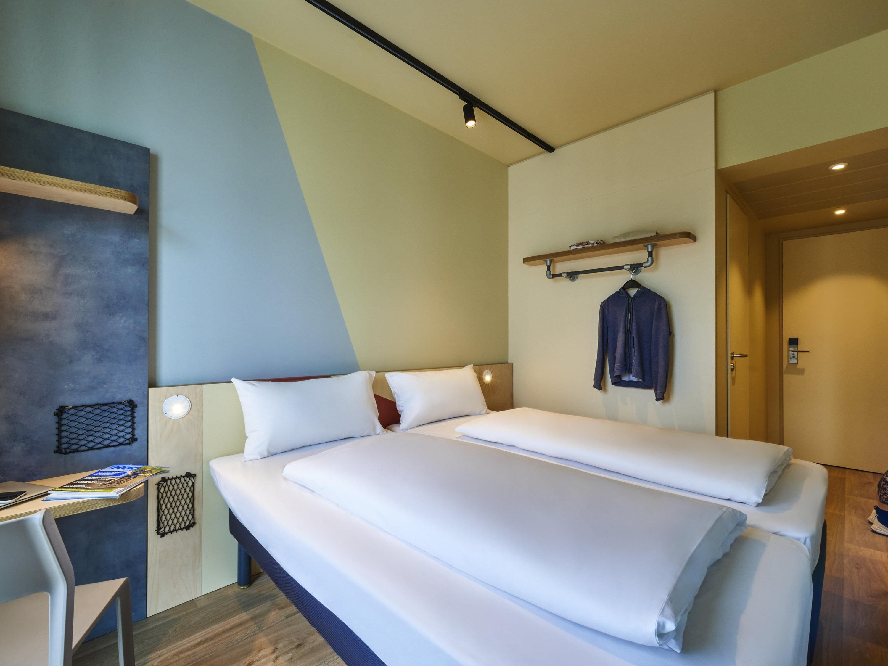 Une chambre d’hôtel avec un lit, un bureau et un porte-manteau.