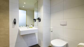 Un baño moderno con lavamanos, espejo y retrete blancos.