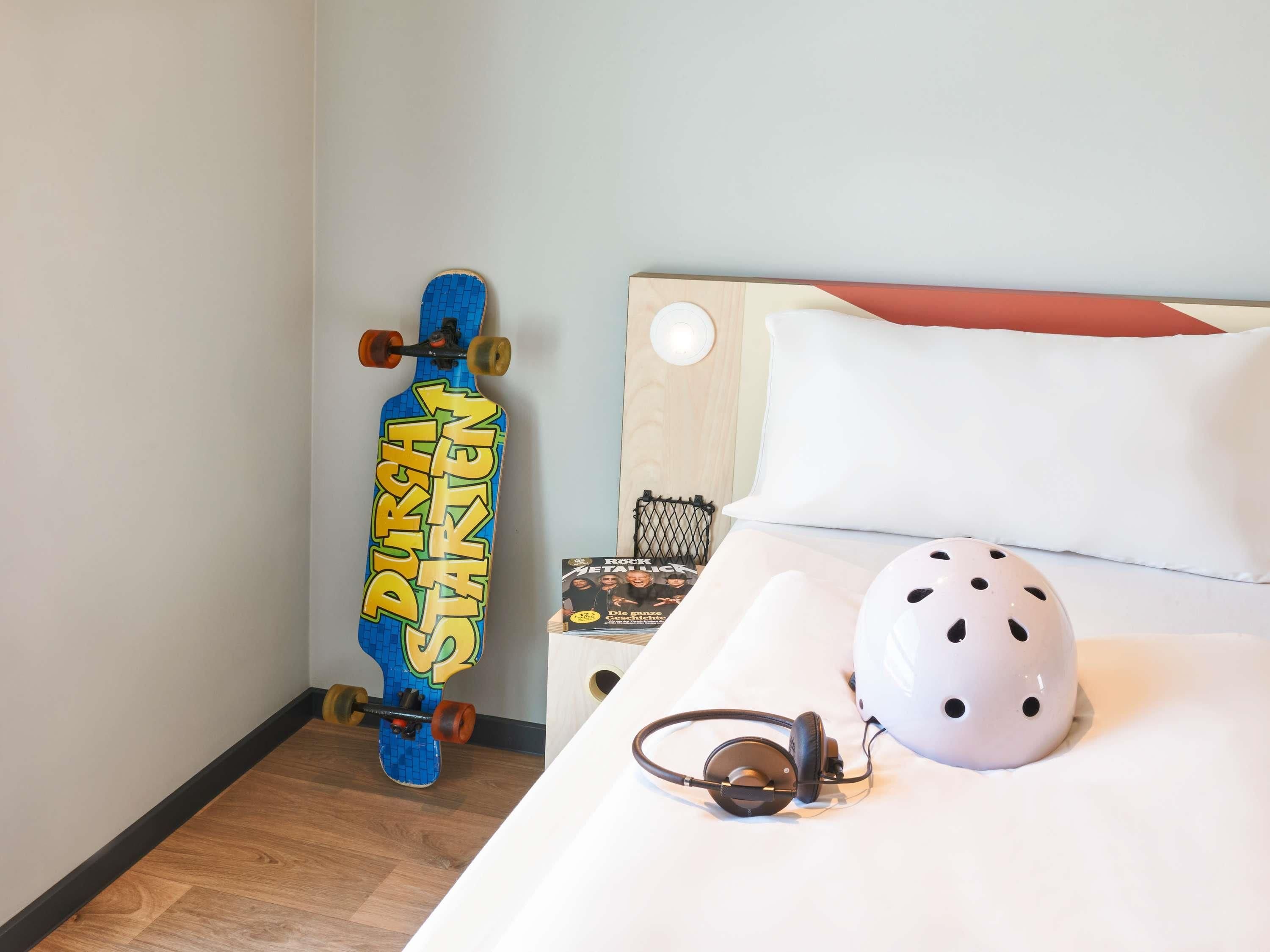Une pièce avec un lit, un skateboard et un casque.