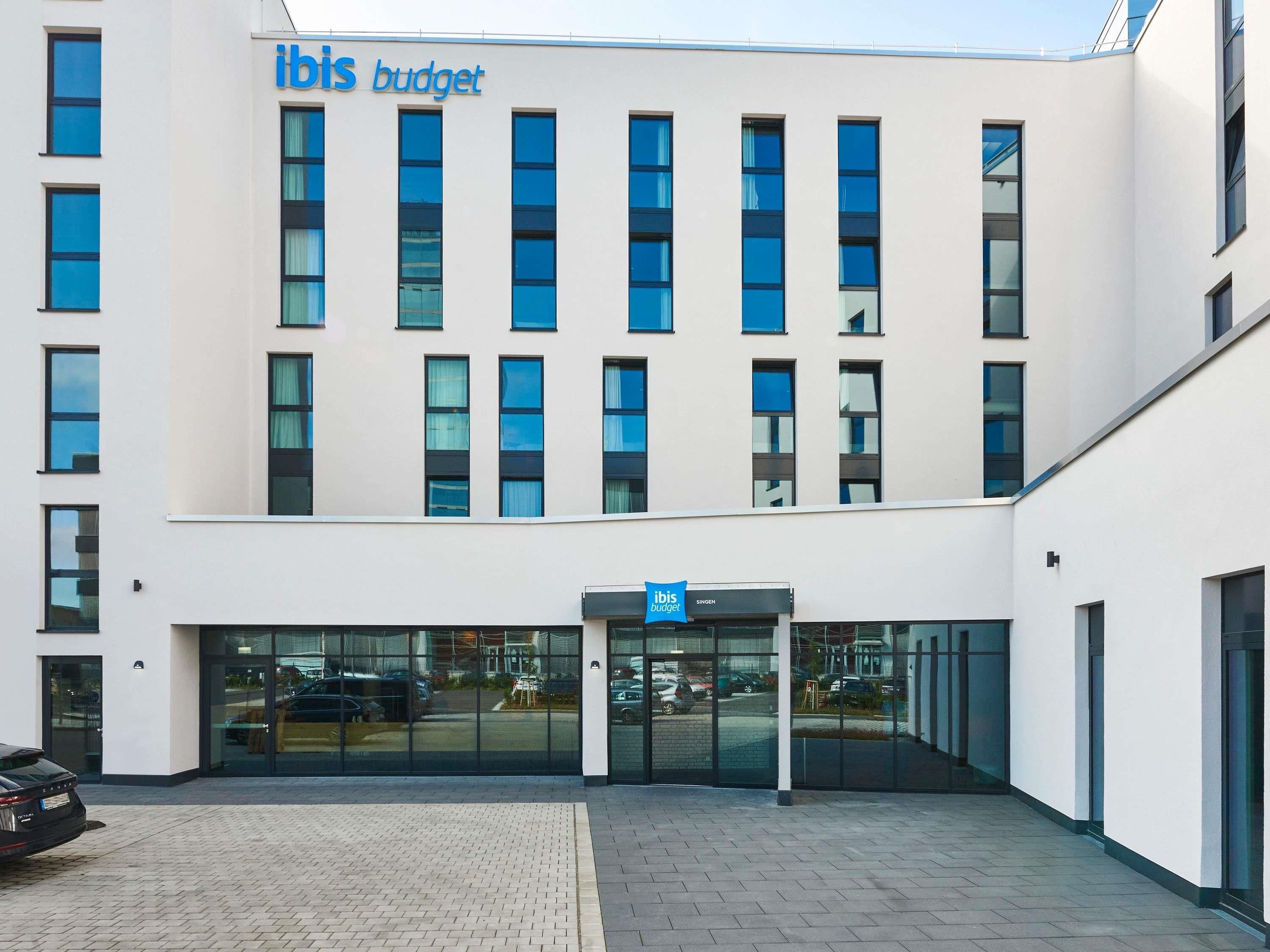 Un edificio moderno con un letrero que dice 'ibis budget' y una entrada de vidrio.
