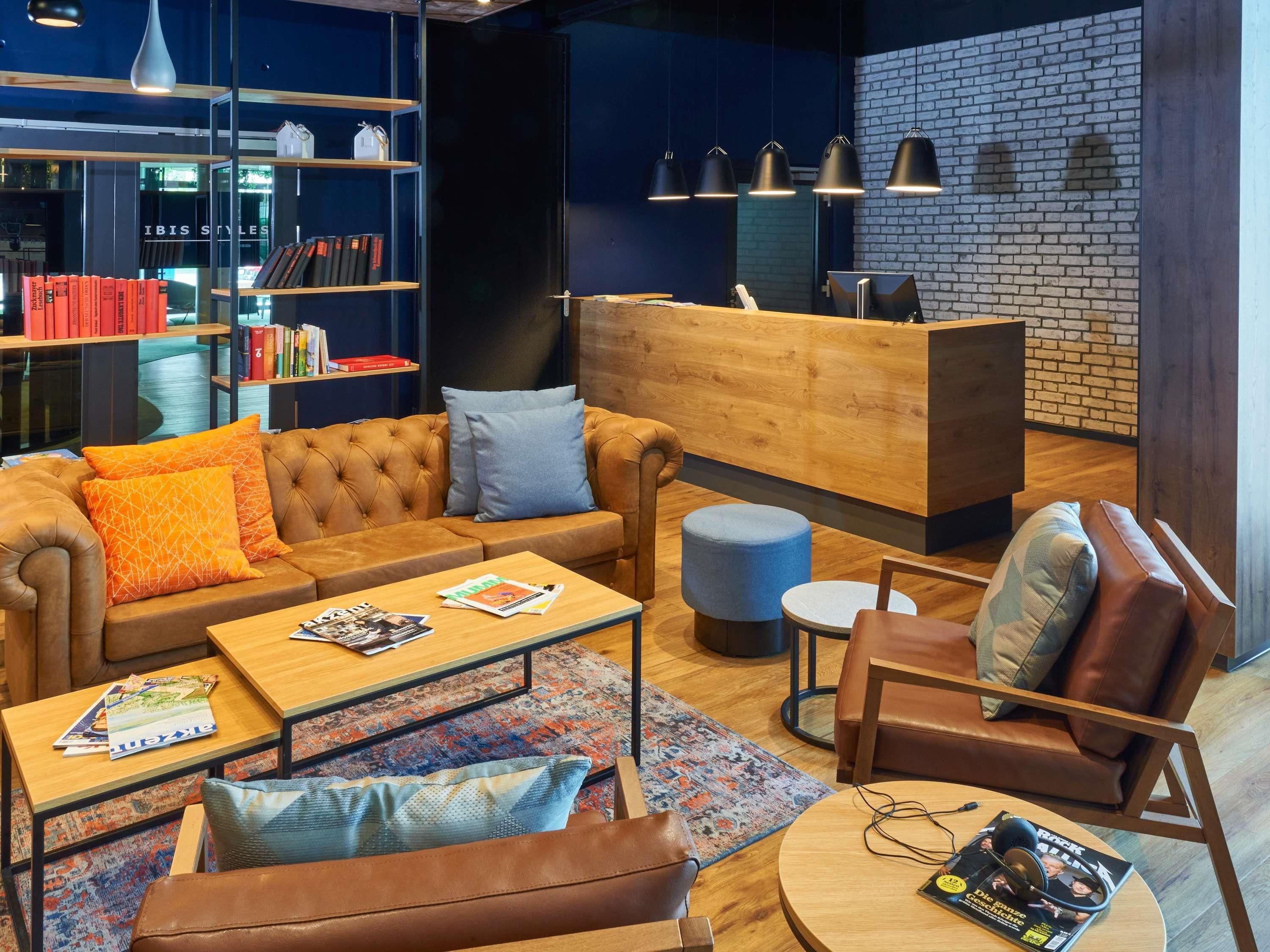 Un área de estar moderna con sofás de cuero, un mostrador de recepción de madera y estanterías llenas de libros.