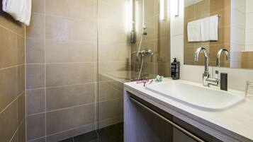 Un baño moderno con un lavamanos grande, espejo y ducha.