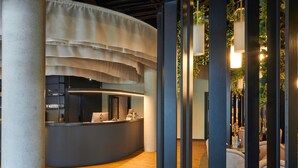 A reception area with a curved counter, a modern design, and a visible office space in the background. - Ibis Styles Singen (Singen)