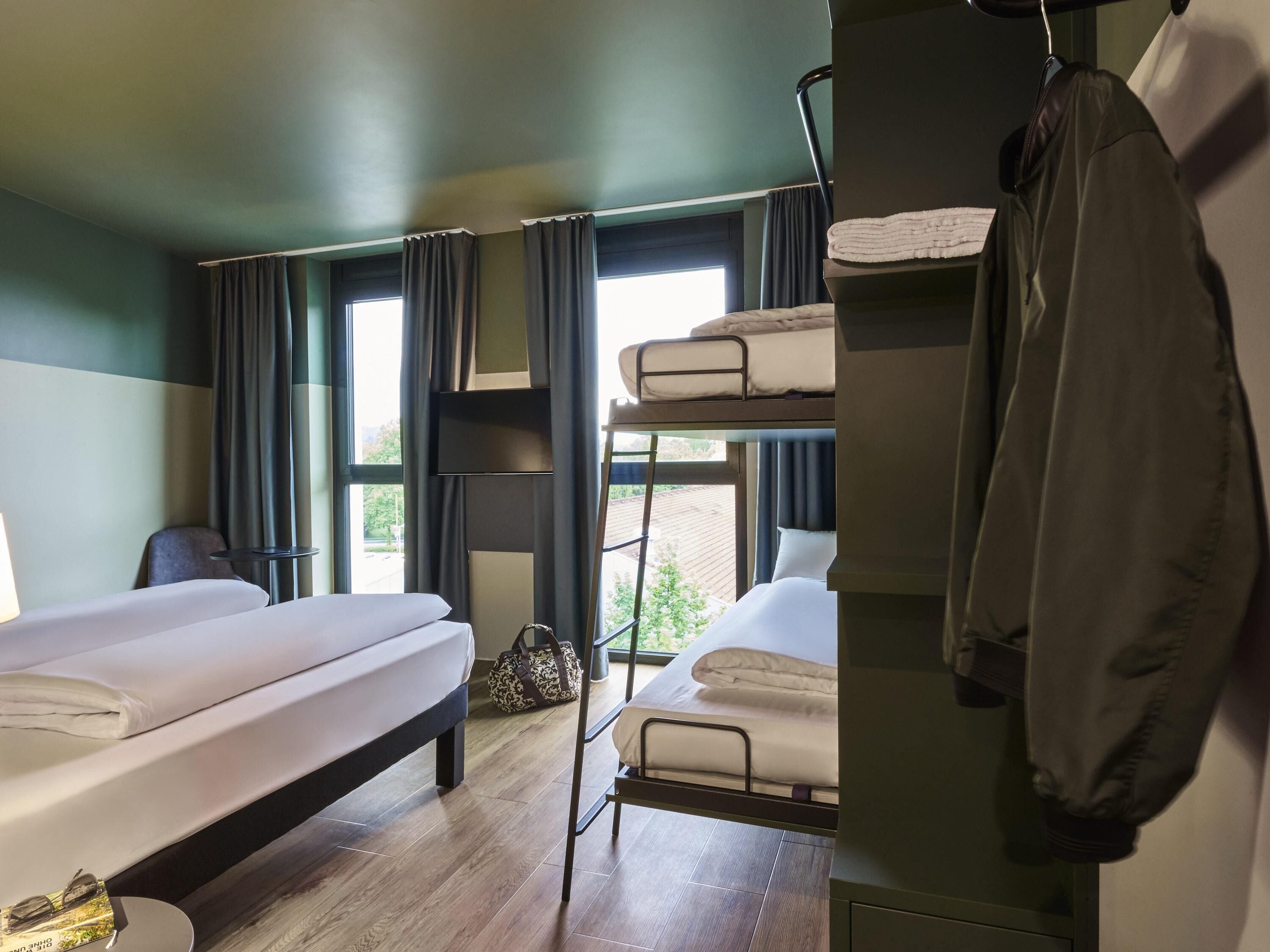 A bunk bed room with a desk, a chair, and a window with curtains.