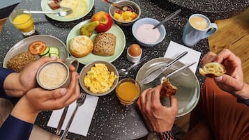 Une table ronde avec un assortiment de produits pour le petit-déjeuner, notamment des œufs, des toasts, des fruits et des boissons.