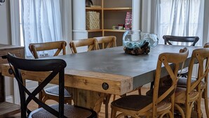 A dining area with a wooden table and chairs, a fish bowl, and a bookshelf with various items. - Luxury living, quick walk to town. King bed. (Eastport)