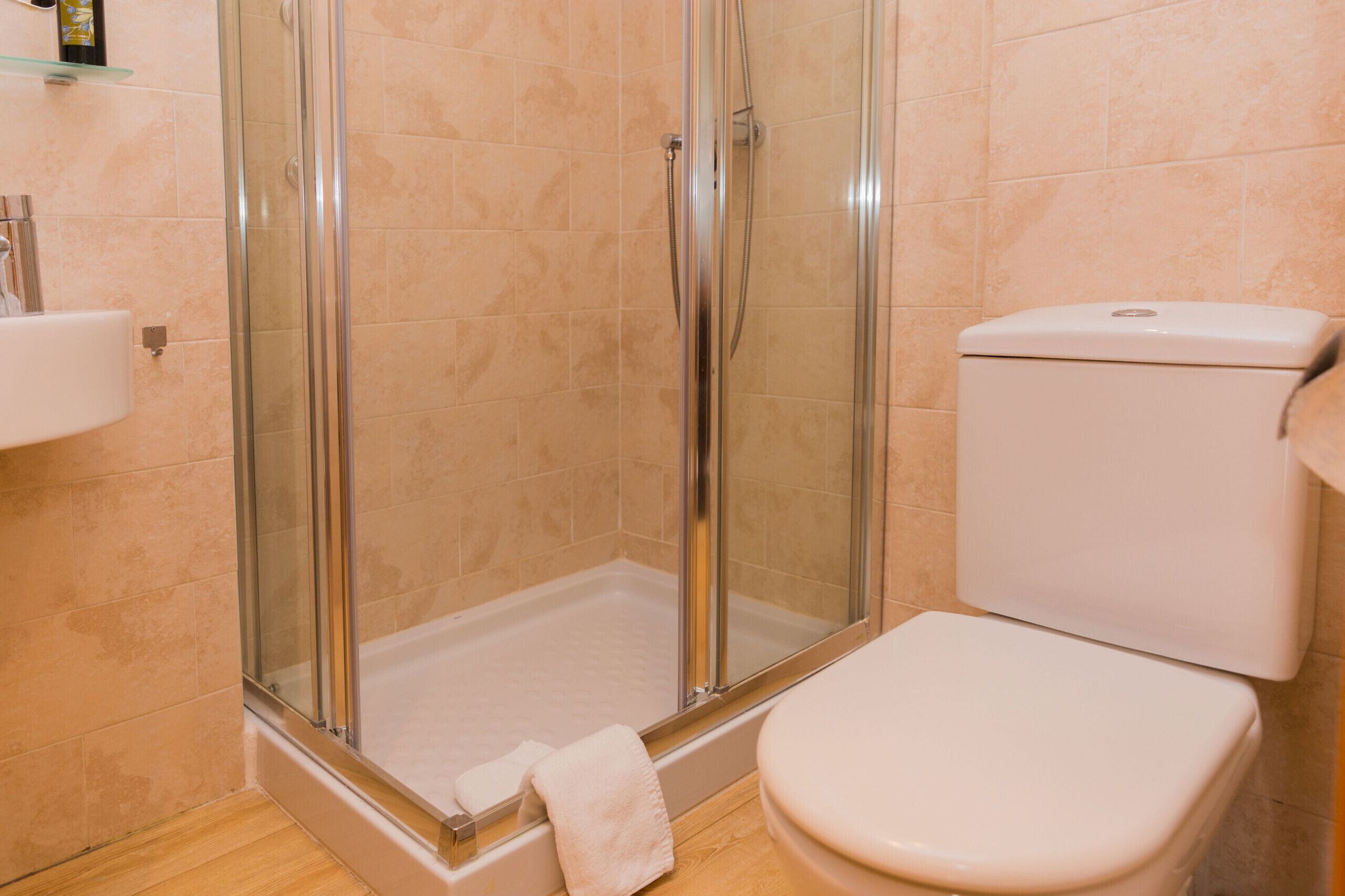 Une salle de bain avec une douche à parois de verre, des toilettes et un lavabo.