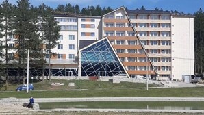A modern building with a unique angular design, surrounded by a grassy area and a body of water. - Hotel Borovi Sjenica (Sjenica)