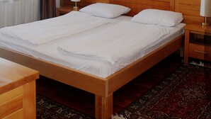 A double bed with wooden headboard, two bedside tables with lamps, a painting on the wall, and a window with curtains. - Hotel Borovi Sjenica (Sjenica)